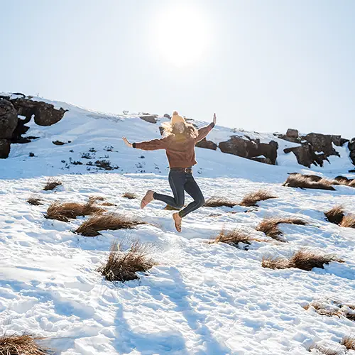 woman jumping on snowy mountains sani pass
